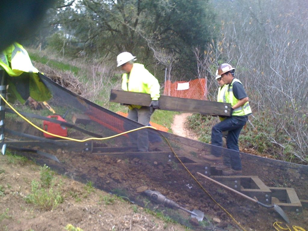 Workers lift a 100-pound box into place to create another tread in the stairway of the trail.