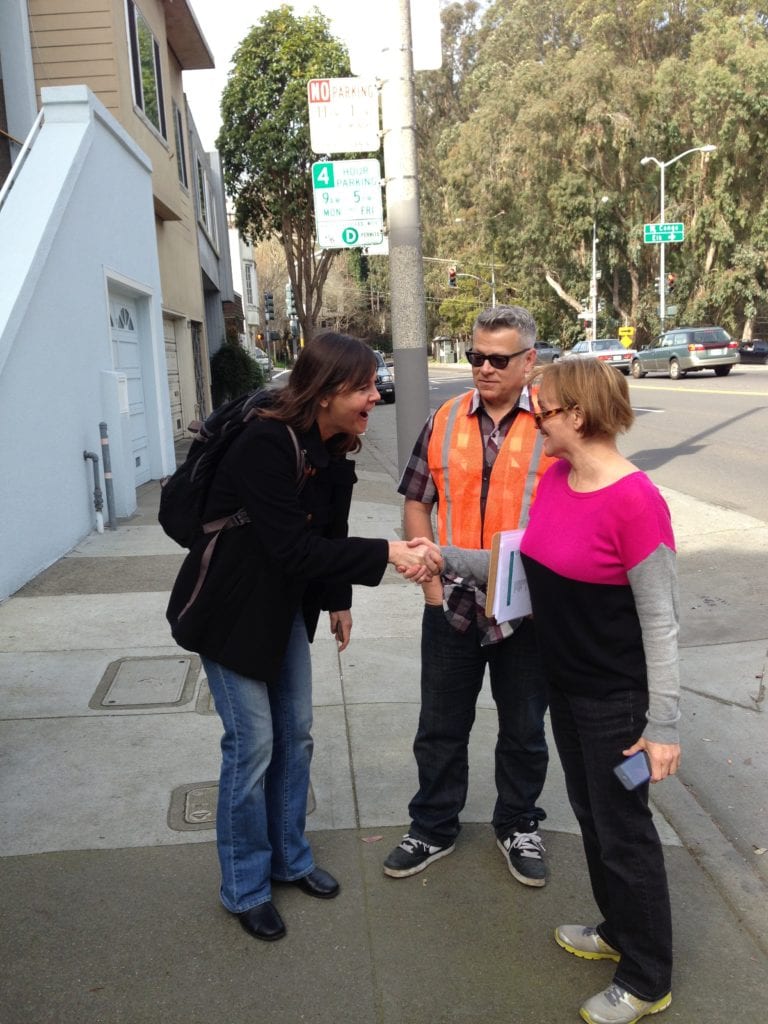 Julia Brashares of San Francisco Parks Alliance greeting Glen Park resident Sylvia Lehnen. John Priola watches wearing the vest he uses when he works in Bosworth Gardens.