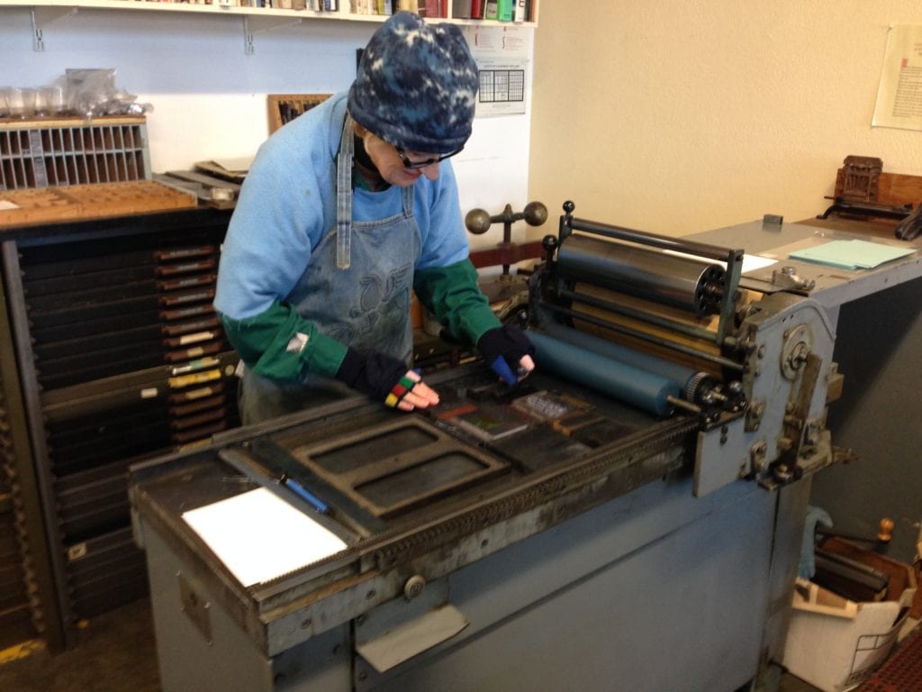 Mary inspecting type, after it has been secured into place in the printer bed.