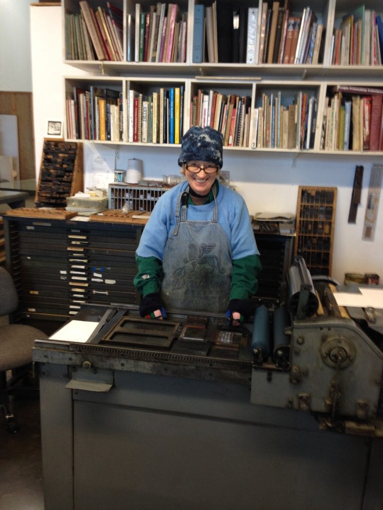 Mary Huizinga standing at her letterpress printer.