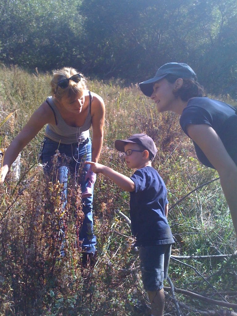 Jenny Sotelo, Rec and Park gardener, pointing out grasses to a little boy and his mother.