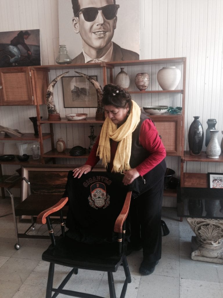 Mia Gonzalez displaying a T-shirt mixing and matching a Day of the Dead mask with San Francisco Giants logo.  