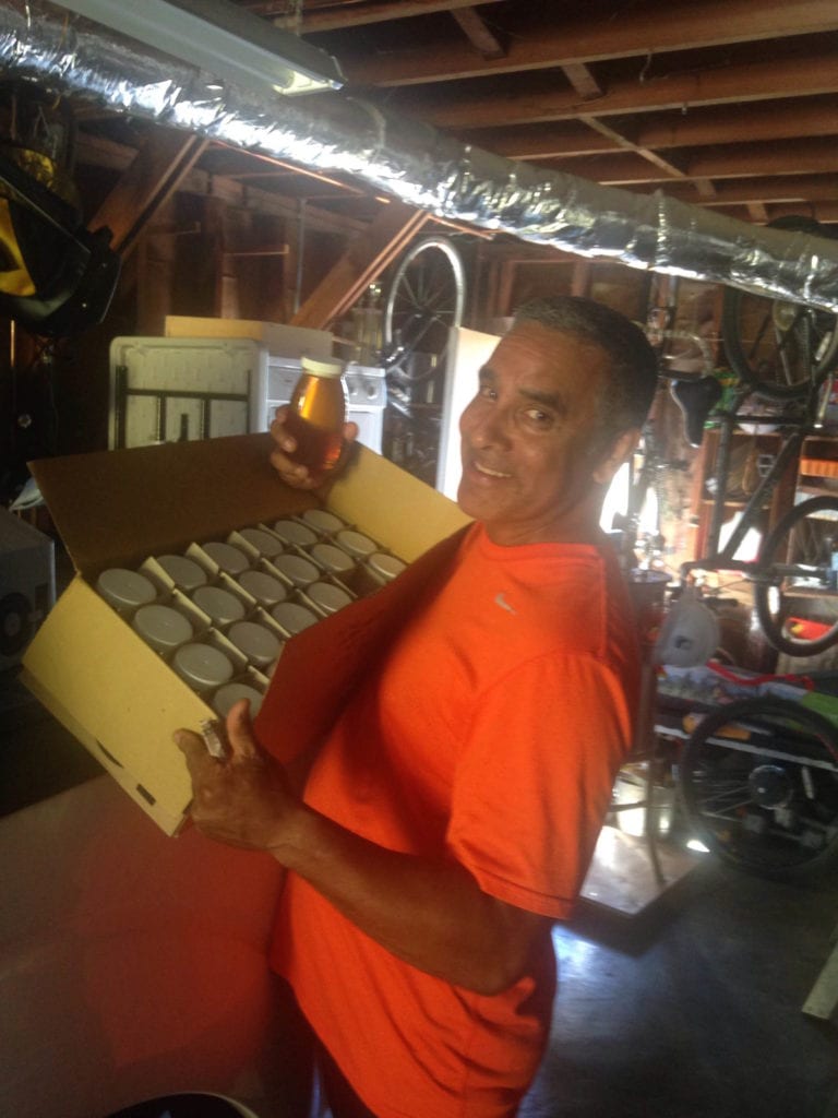 Fernando Aguilar holding up one of 32 bottles of honey extracted from his two School Farm beehives